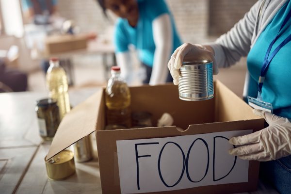 Close-up of volunteer packing donation boxes while working at food bank.