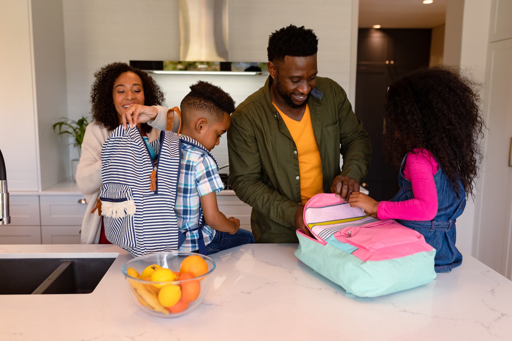 Happy african american parents and children preparing backpacks for school